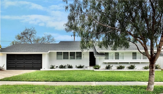 ranch-style home with stucco siding, roof with shingles, concrete driveway, a front yard, and a garage