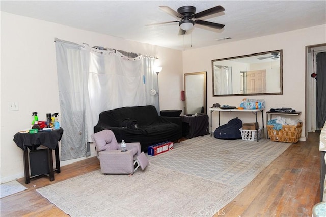 sitting room with wood finished floors, ceiling fan, visible vents, and baseboards