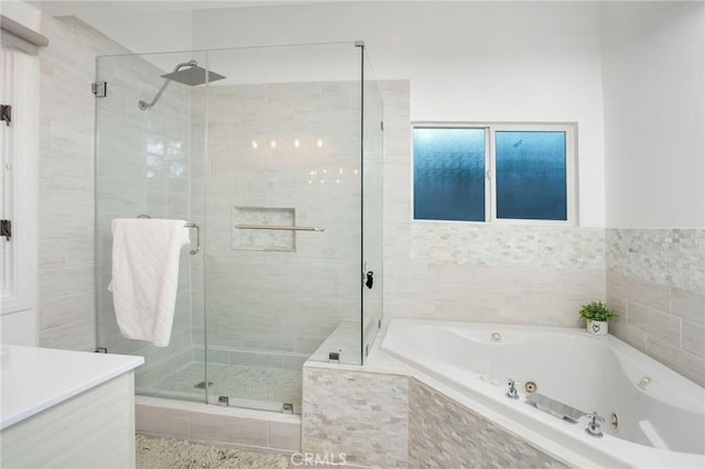 full bathroom featuring a shower stall, a jetted tub, and vanity