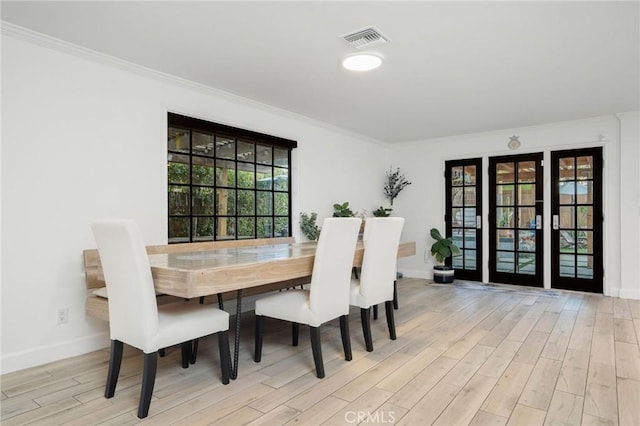 dining space with crown molding, wood finished floors, visible vents, and baseboards