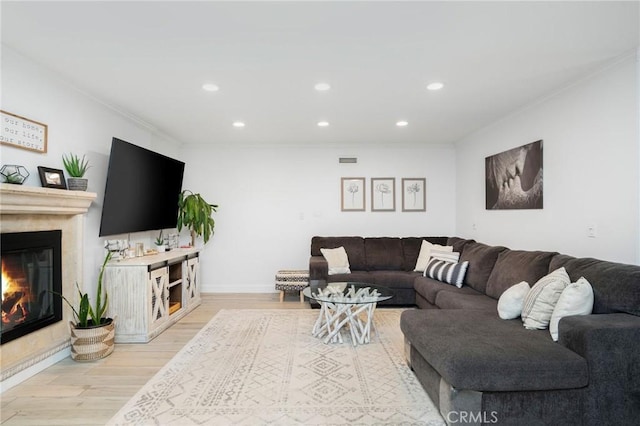 living room with visible vents, ornamental molding, a high end fireplace, recessed lighting, and light wood finished floors