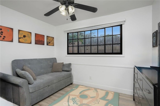 sitting room featuring a ceiling fan, light wood-style floors, and baseboards