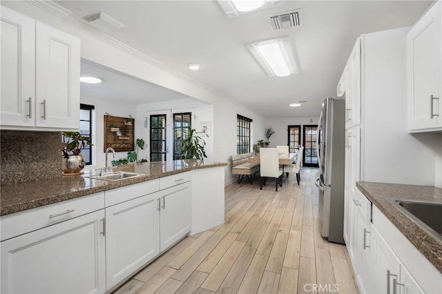 kitchen featuring light wood-type flooring, visible vents, freestanding refrigerator, and a sink