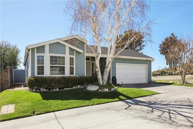 view of front facade with driveway, fence, board and batten siding, a front yard, and a garage