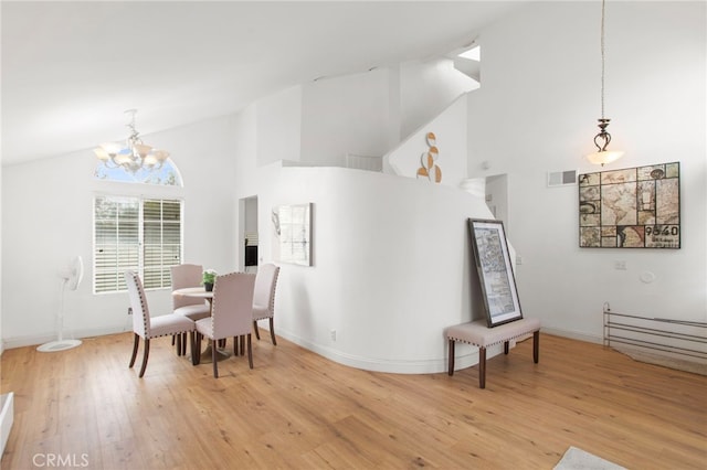 dining room featuring wood finished floors, baseboards, visible vents, high vaulted ceiling, and an inviting chandelier