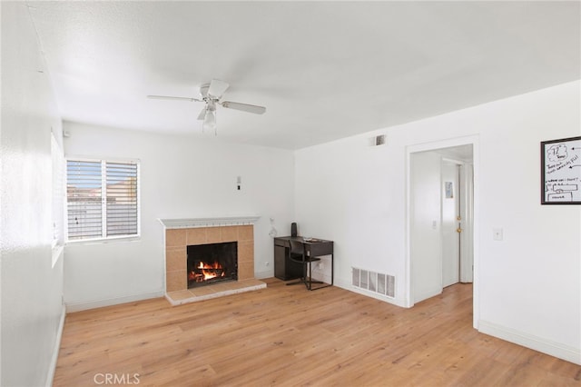 unfurnished living room with a fireplace, wood finished floors, visible vents, and ceiling fan