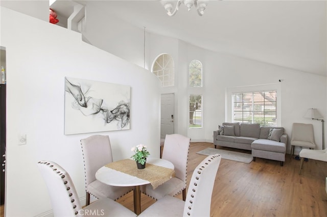 dining space with light wood-style floors and high vaulted ceiling