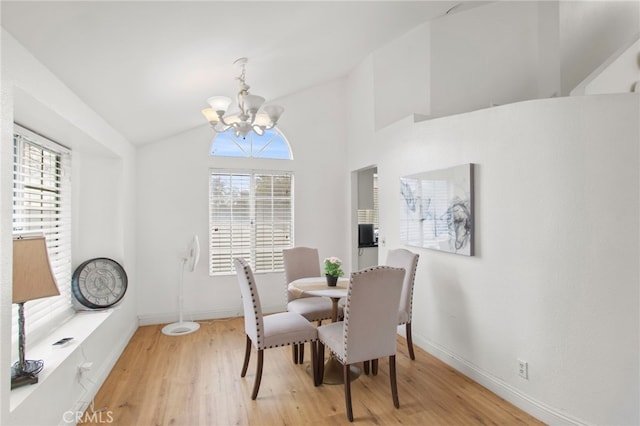 dining area featuring a notable chandelier, plenty of natural light, light wood-style floors, and vaulted ceiling