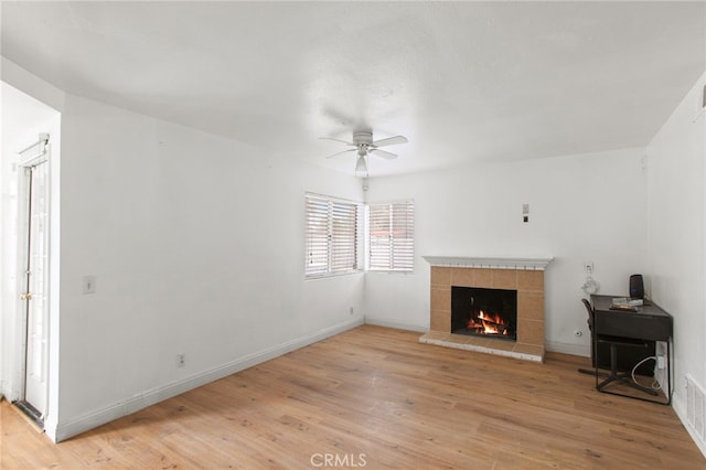 living room featuring visible vents, a ceiling fan, light wood-style floors, a fireplace, and baseboards