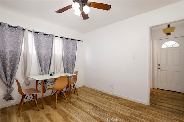 dining space featuring a ceiling fan, wood finished floors, and baseboards