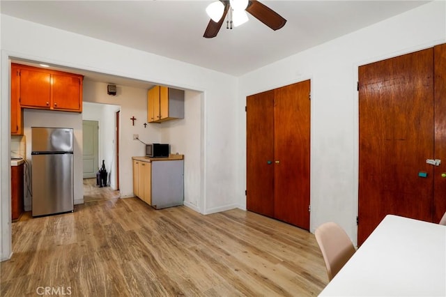 kitchen with brown cabinets, light wood finished floors, a ceiling fan, stainless steel appliances, and light countertops