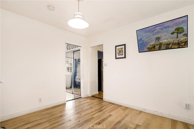 spare room with baseboards and light wood finished floors