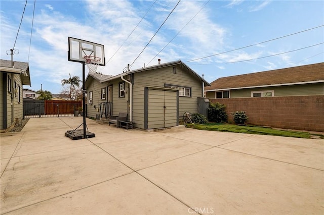 rear view of house featuring a gate, a patio, concrete driveway, and fence