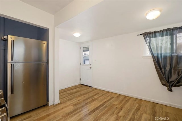 kitchen featuring baseboards, light wood-style floors, and freestanding refrigerator