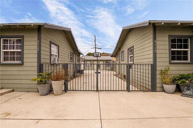 view of home's exterior with a gate, a patio area, an outdoor structure, and fence