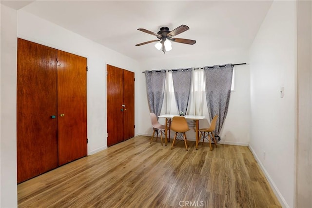 living area with baseboards, wood finished floors, and a ceiling fan