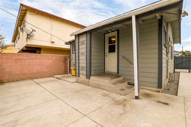 view of exterior entry with a patio and fence