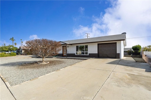 ranch-style home featuring a garage, brick siding, driveway, and fence