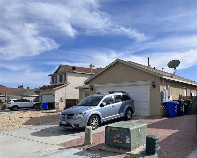 view of front of property with an attached garage, fence, driveway, and stucco siding