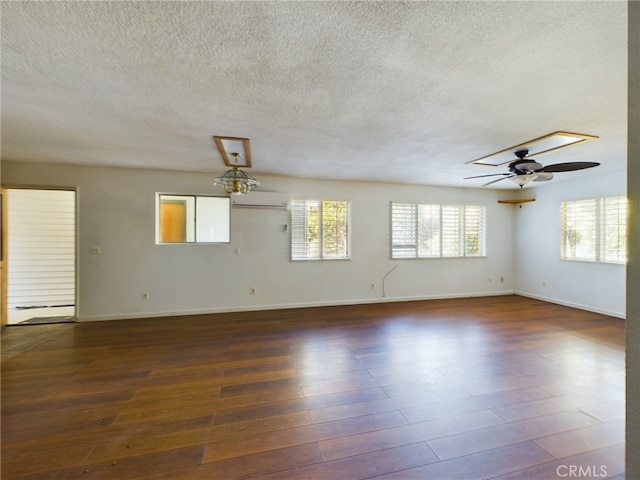 spare room featuring wood finished floors, baseboards, ceiling fan, an AC wall unit, and a textured ceiling