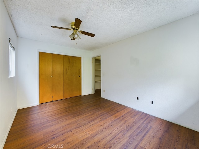 unfurnished bedroom with a ceiling fan, wood finished floors, a closet, and a textured ceiling