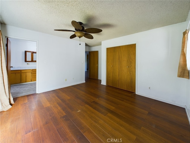 unfurnished bedroom featuring a closet, baseboards, a textured ceiling, and dark wood-style floors