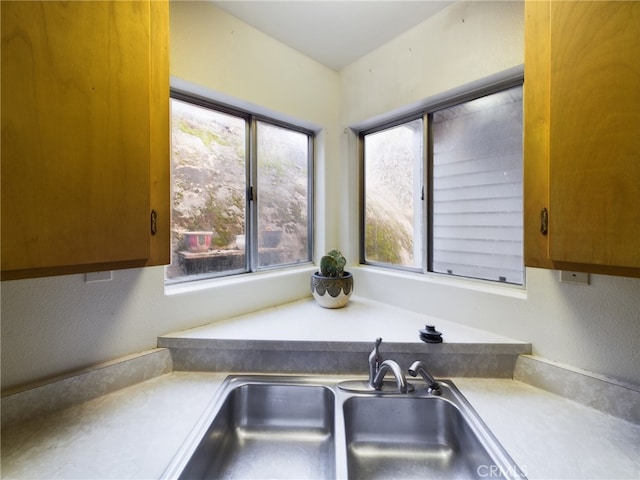 kitchen with light countertops, brown cabinetry, and a sink