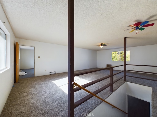 carpeted empty room with ceiling fan and a textured ceiling