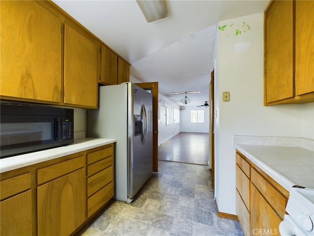 kitchen featuring black microwave, light countertops, refrigerator with ice dispenser, brown cabinets, and range