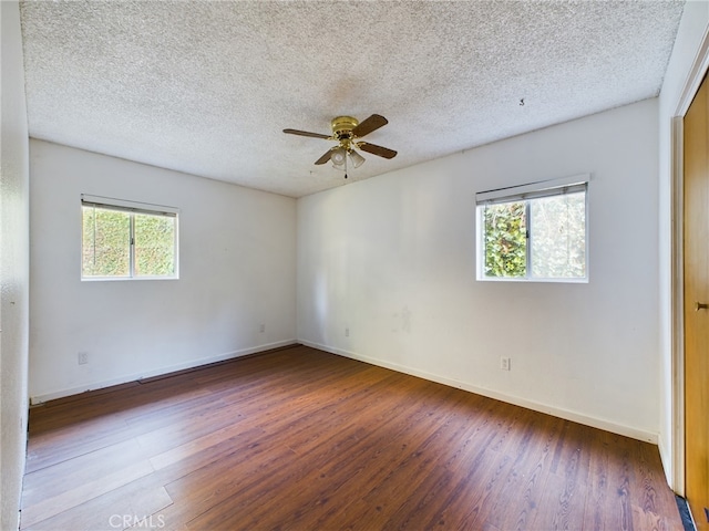 empty room with ceiling fan, a textured ceiling, baseboards, and wood finished floors