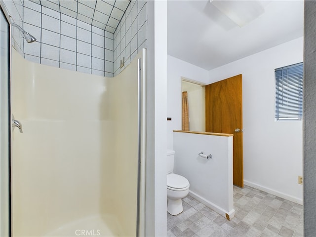 bathroom featuring a shower stall, toilet, and baseboards