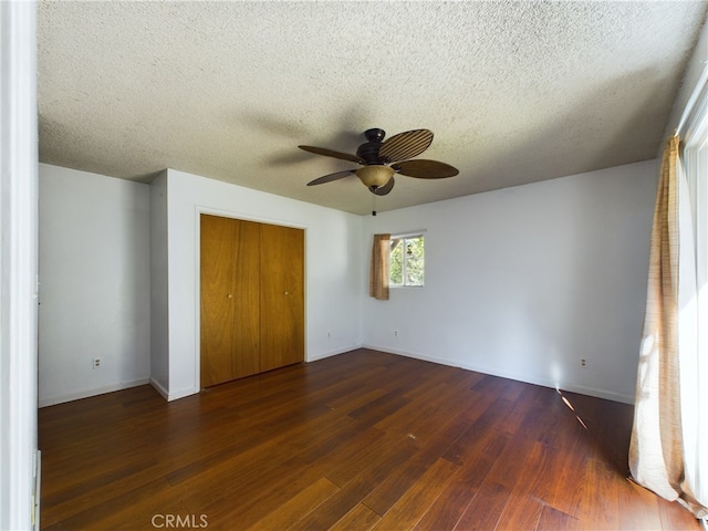 unfurnished bedroom featuring a ceiling fan, hardwood / wood-style flooring, a textured ceiling, a closet, and baseboards