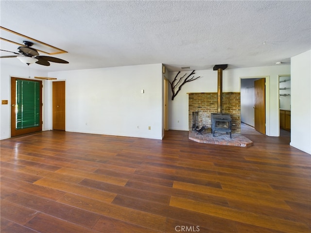 unfurnished living room featuring ceiling fan, a textured ceiling, wood finished floors, and a wood stove