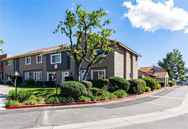 multi unit property featuring a tile roof and stucco siding