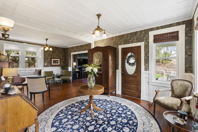 foyer entrance featuring wallpapered walls, an inviting chandelier, and a wainscoted wall