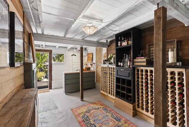 wine area featuring beamed ceiling, wooden walls, and wooden ceiling