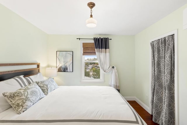 bedroom featuring baseboards and dark wood-style flooring