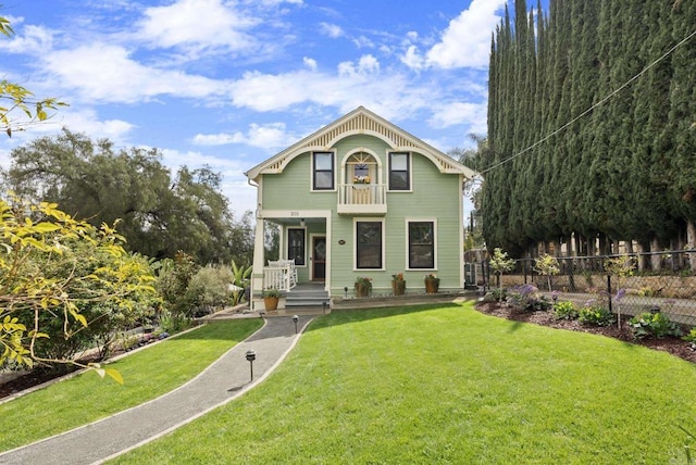 view of front facade with a porch, a front yard, and fence