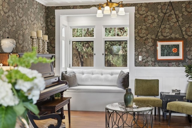 living room with a wainscoted wall, wood finished floors, crown molding, and wallpapered walls