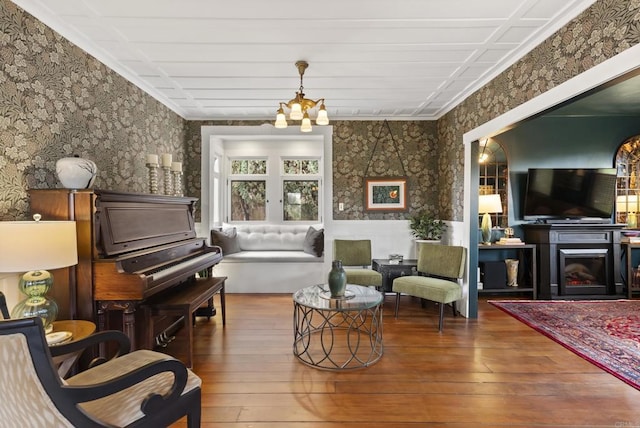 sitting room with a notable chandelier, a warm lit fireplace, and hardwood / wood-style floors