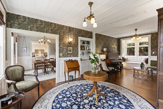 living area featuring a chandelier, a wainscoted wall, and wallpapered walls