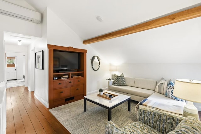 living area featuring lofted ceiling with beams, wood-type flooring, baseboards, and a wall mounted air conditioner