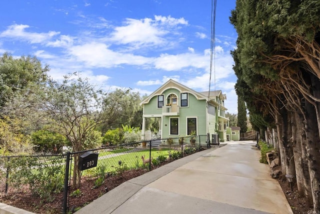 view of front of home featuring a fenced front yard, cooling unit, and a balcony