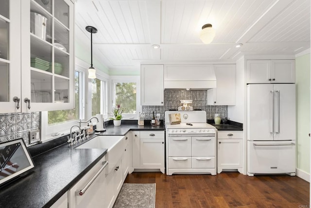 kitchen with white cabinetry, white appliances, dark countertops, and a sink