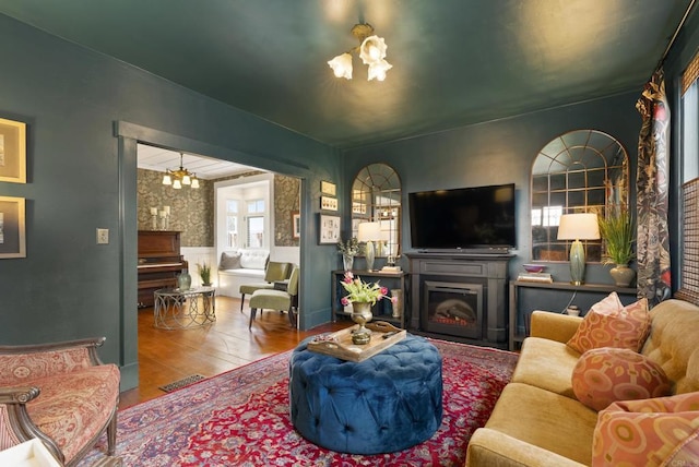 living area with a notable chandelier, a fireplace, a wainscoted wall, and wood finished floors