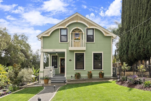 view of front of house with covered porch, a front yard, and fence