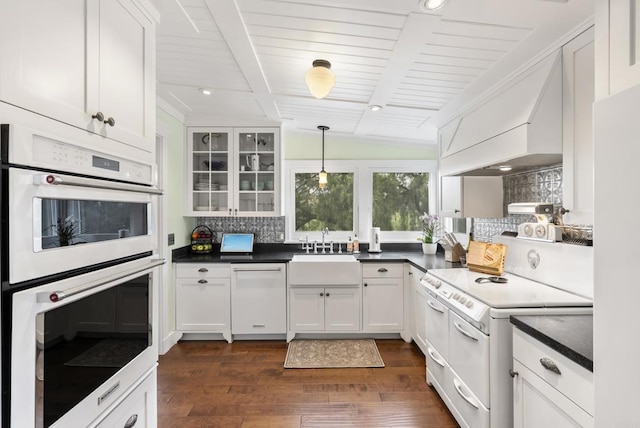 kitchen featuring a sink, custom range hood, decorative backsplash, white appliances, and dark wood-style flooring