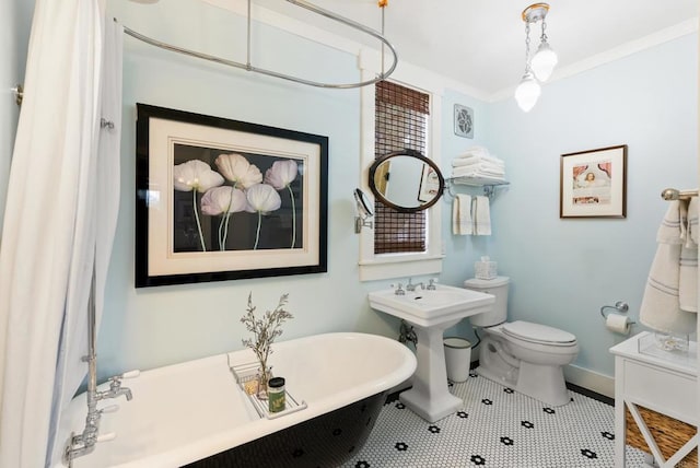 bathroom featuring crown molding, baseboards, toilet, tile patterned floors, and a soaking tub