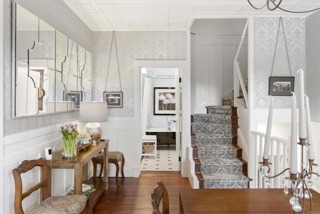 interior space featuring wallpapered walls, a wainscoted wall, wood-type flooring, and a decorative wall