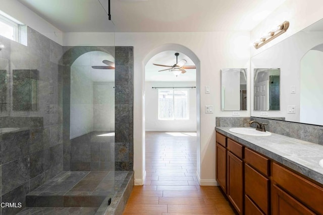 full bathroom with a ceiling fan, a sink, wood finished floors, double vanity, and walk in shower